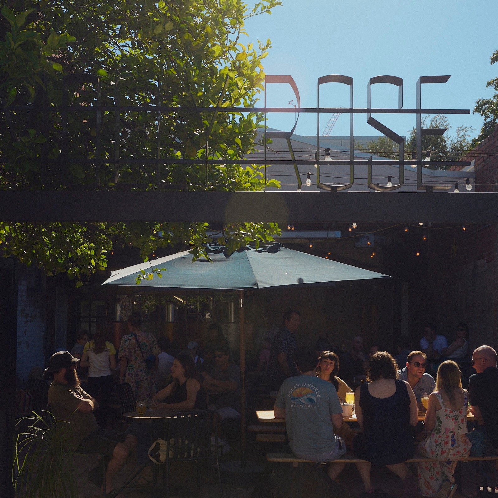 People sitting under a large umbrella at a brewery beer garden with 'MOLLY Rose' sign in the background.